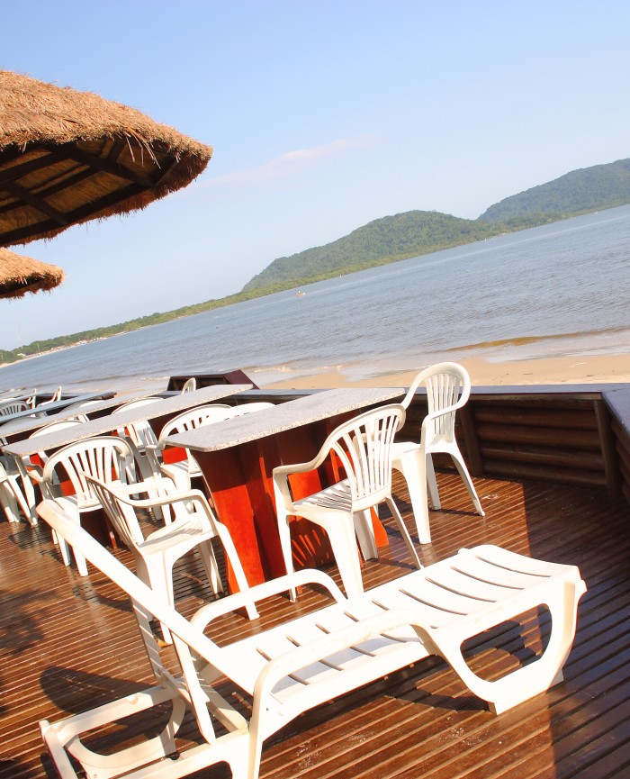 Deck da Pousada Pôr do Sol com cadeira de praia, mesas e cadeiras do restaurante